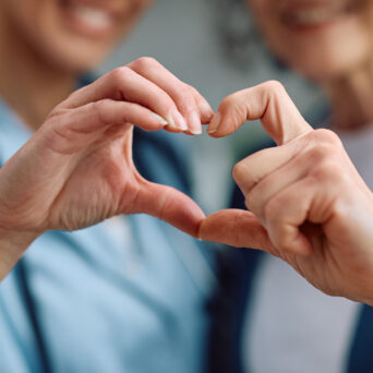 elderly woman and her healthcare provider making hears with their hands